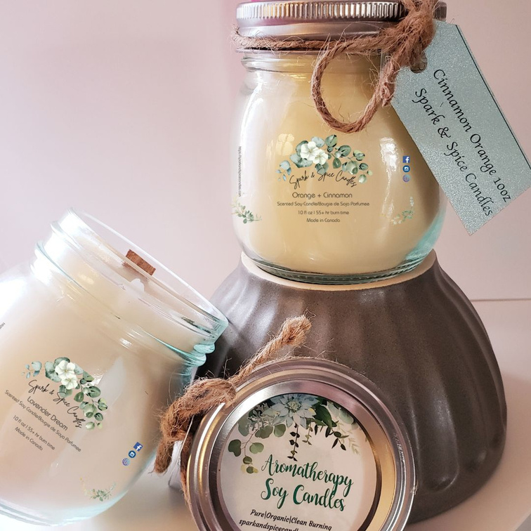 One 10oz soy candle is glass jar, with a woodwick, leaning to the right. It's lid is sitting against a prop bowl.
On top of the bowl sits another 10oz glass jar soy candle with a decorative twine wrapped around its neck.