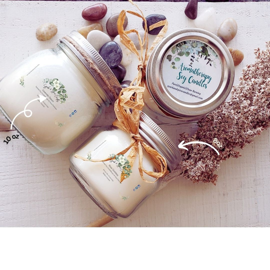 3 soy candles in 10 oz, and 8oz glass jars, each adorned with a pretty bow of twine or raffia wrapped around the  neck of the jars.  